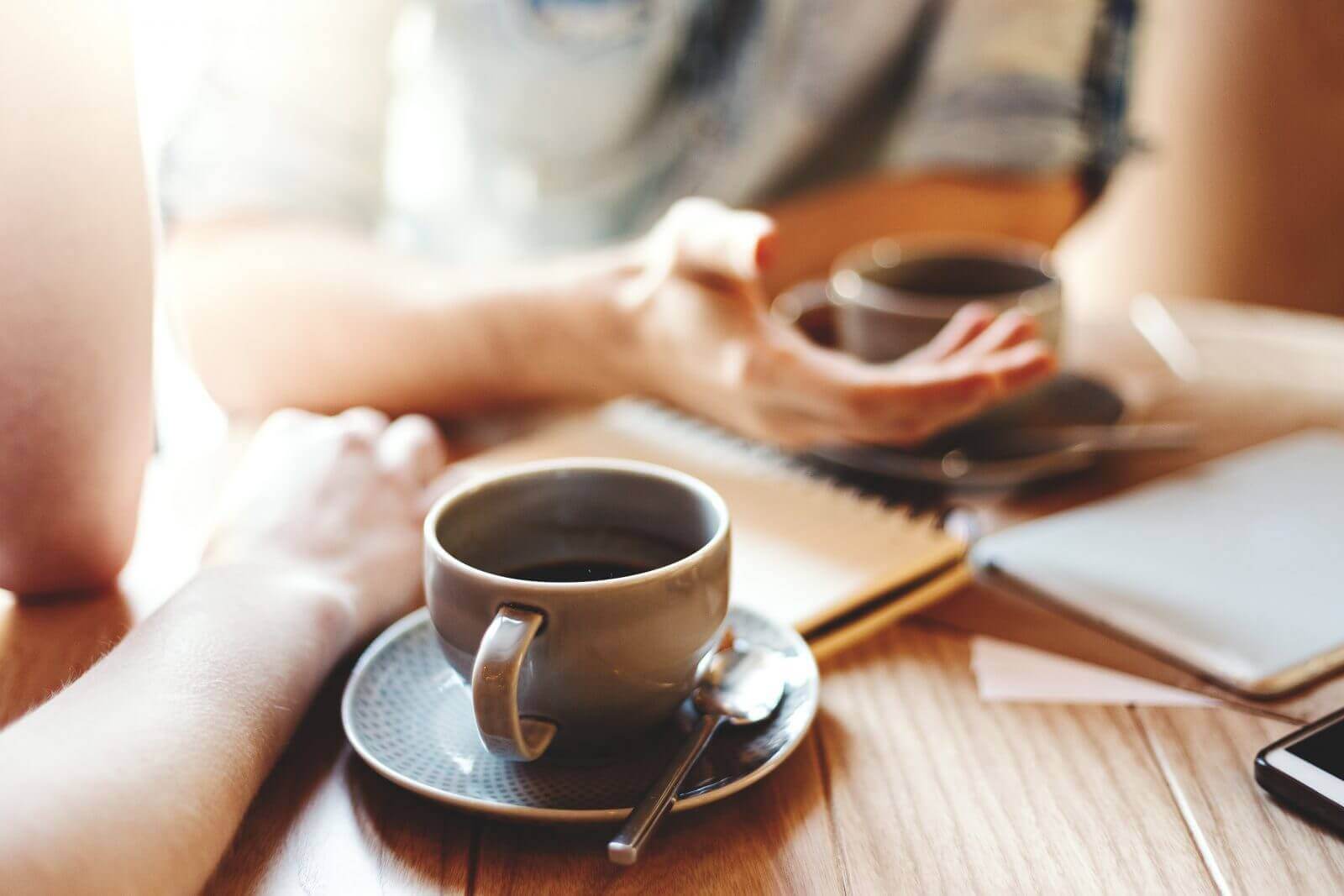 Business meeting over coffee with notebooks and smartphone on wooden table.