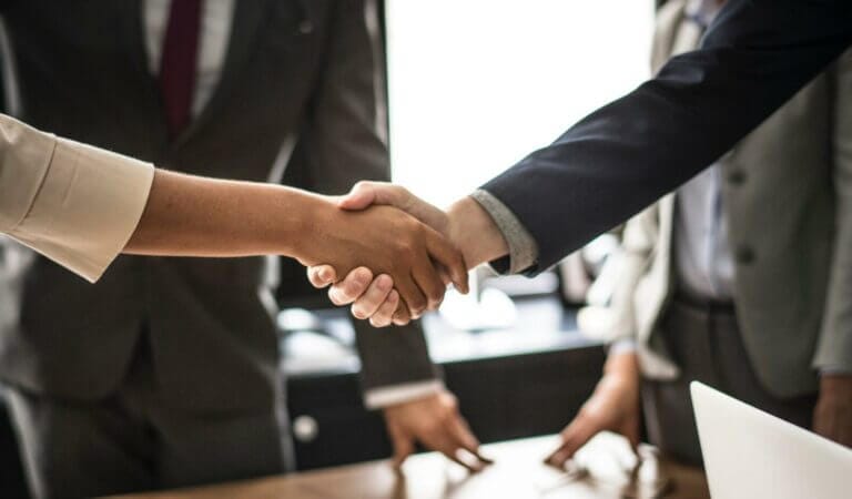 Business handshake between professionals in formal attire, symbolizing partnership and agreement in a corporate setting.