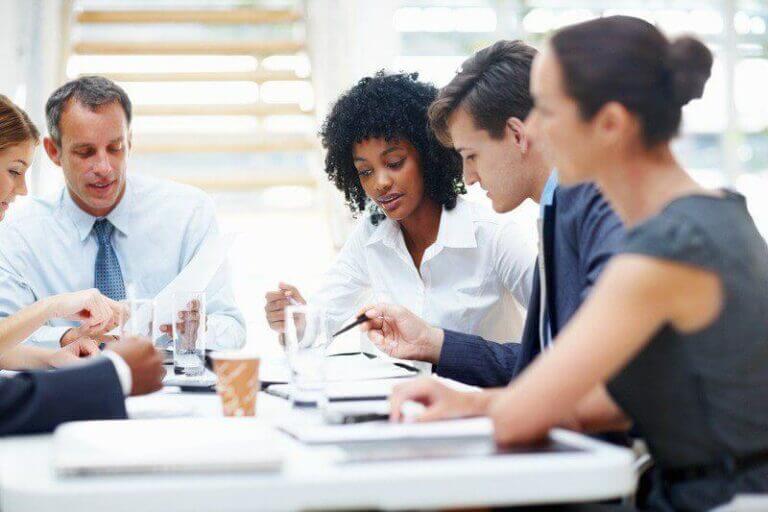 Colleagues in a board meeting discussing documents and using tablets, highlighting teamwork and collaboration.