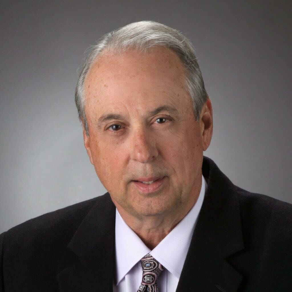Senior business professional in suit, gray background, representing Premise Health leadership.
