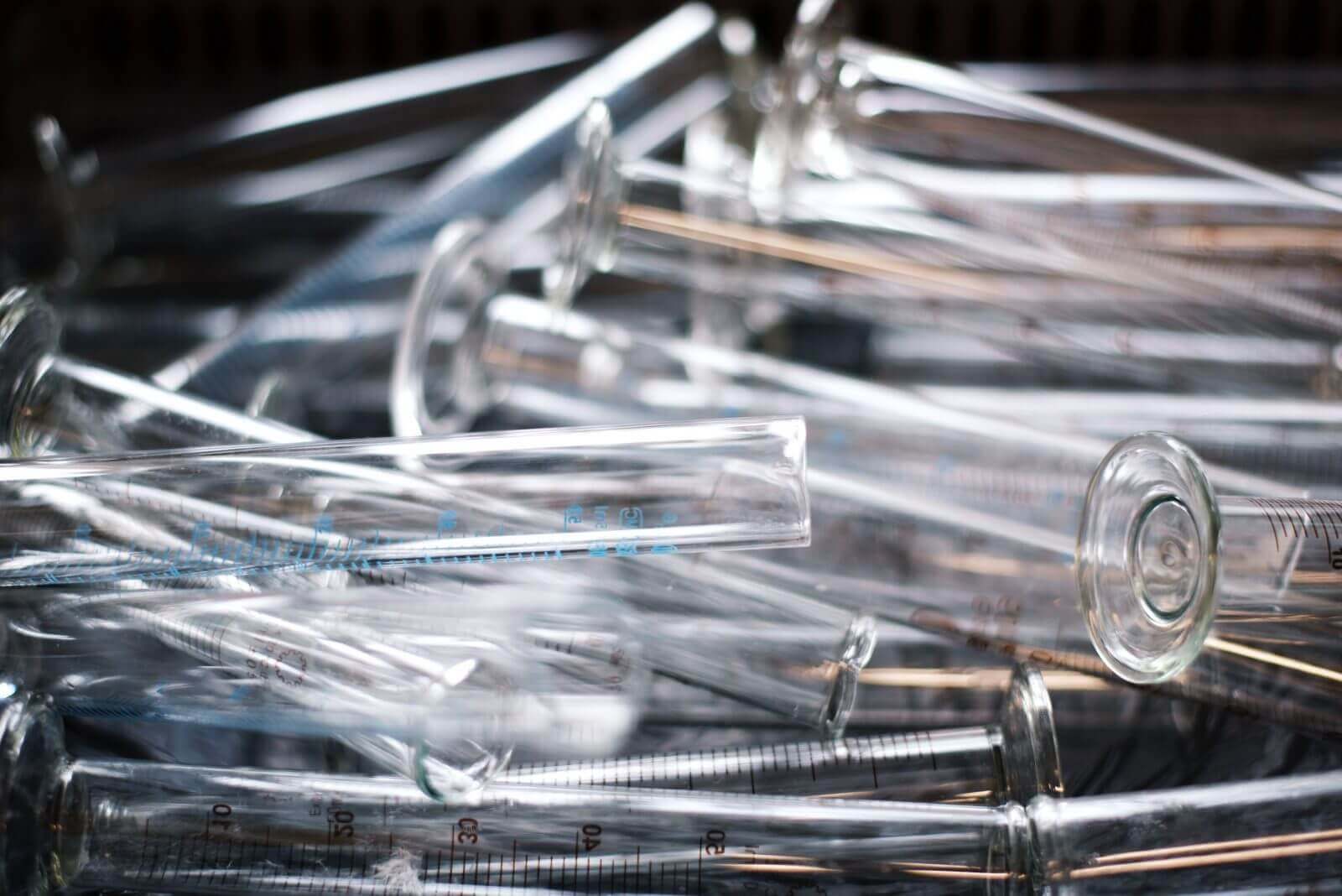 Pile of transparent glass test tubes with measurement markings, laboratory equipment for scientific experiments.