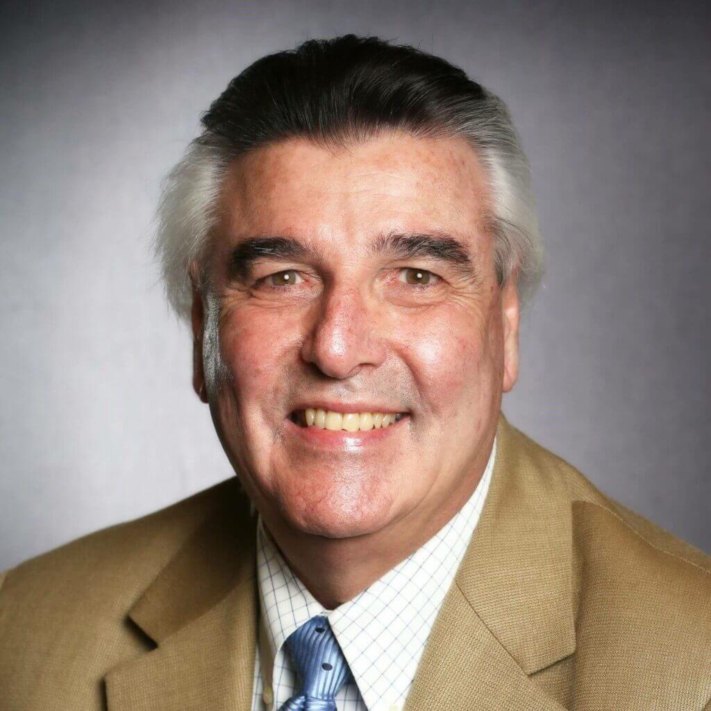 Smiling man in a suit and tie, professional headshot, gray background, business portrait, middle-aged male.