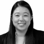 Black and white portrait of a smiling woman with long hair, wearing a blazer.