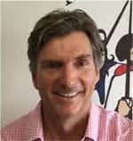 Don't know who this is, smiling person in pink shirt with artwork in background.