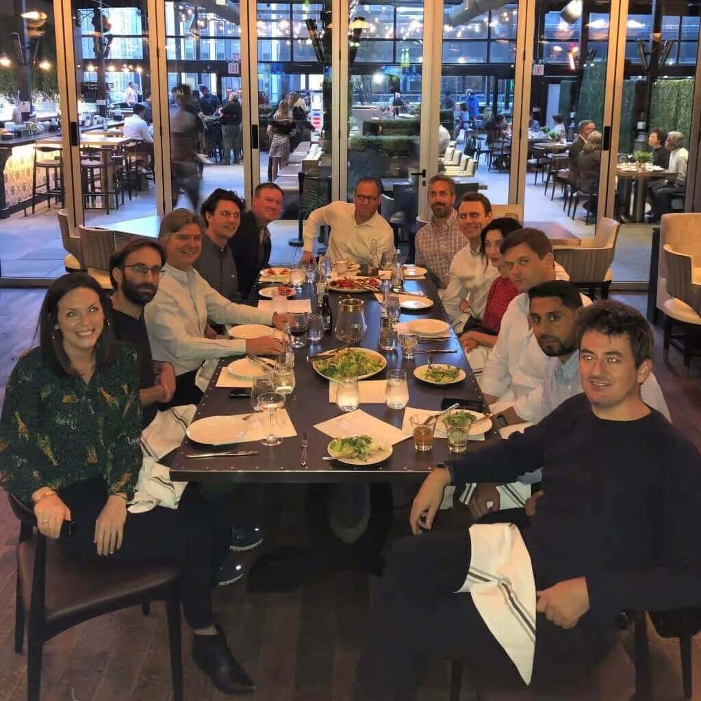 Team dinner event with colleagues at upscale restaurant, enjoying meals and camaraderie, large group dining experience.