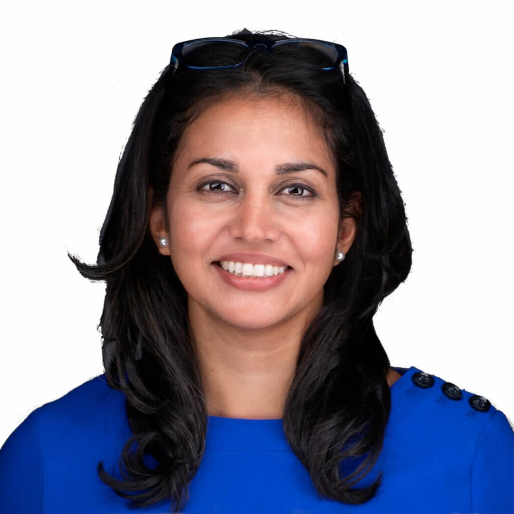 Smiling woman with long dark hair wearing a blue top with buttons, white background.