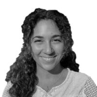 Isabella Hanna BW silo Smiling woman with curly hair in black and white portrait, isolated on white background.